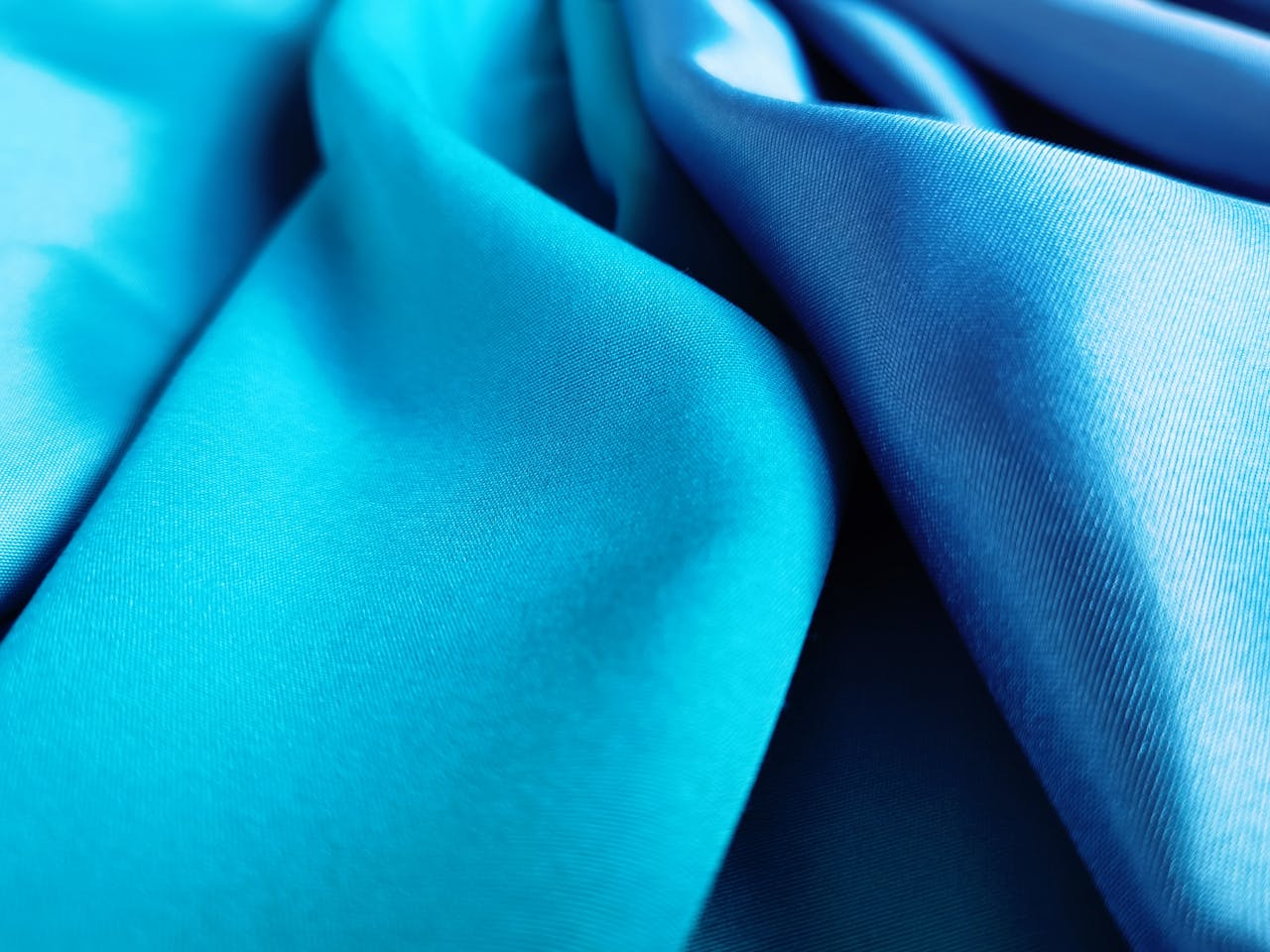 Close-up of vivid blue silk fabric showcasing elegant folds and texture.